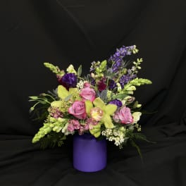 Mixed bouquet in a purple vase with pink, yellow, and purple flowers