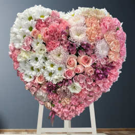 Heart-shaped floral arrangement of pink and white flowers on a stand