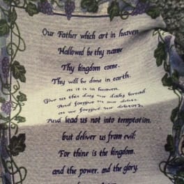 Decorative wall hanging with the Lord's Prayer framed by vines and purple flowers