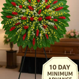 Large circular standing spray with red tropical flowers and yellow and white blooms on a green leaf backdrop