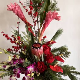Tall tropical arrangement with pink ginger, red roses, and orchids in a wooden container