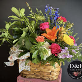 Mixed bouquet in a woven basket with bright roses and lilies