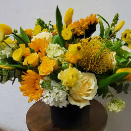 Yellow and white mixed flower arrangement in a black vase