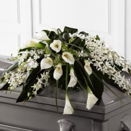 White calla lilies and small white flowers arranged on a casket