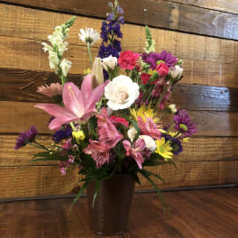 Mixed bouquet in a brown vase with pink lilies and purple flowers