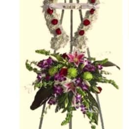 Standing funeral wreath on an easel with red roses and purple flowers