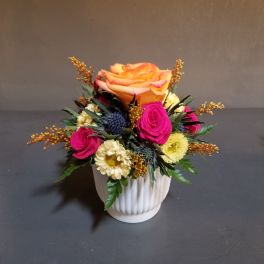 Mixed bouquet in a white ribbed vase with orange and pink roses