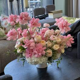 Pink and cream floral arrangement in a white vase on a table
