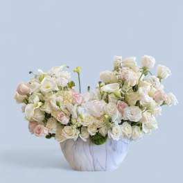 White and blush roses with calla lilies in a marble-look vase