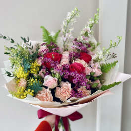 Hand-tied bouquet of pink and red roses with purple accents