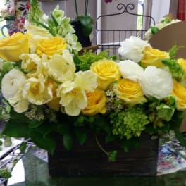 Yellow and white roses arranged in a dark rectangular container
