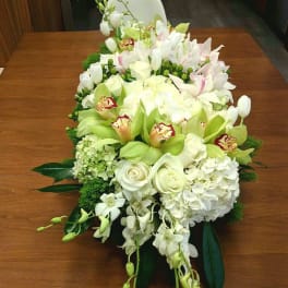 Large white and green floral arrangement with orchids and roses