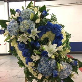 Large blue and white floral standing spray with roses, lilies, and hydrangeas