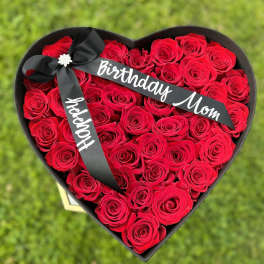 Heart-shaped box of red roses with a black ribbon reading Birthday Mom