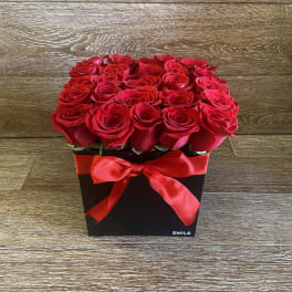 Red roses arranged in a black square box with a red ribbon