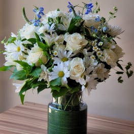White and blue mixed flower bouquet in a glass vase