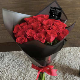 Bouquet of red roses wrapped in black paper with a red ribbon
