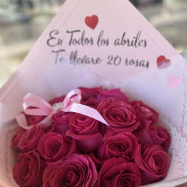 Bouquet of deep pink roses wrapped in pale pink paper with a ribbon