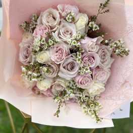 Bouquet of pale pink and white roses wrapped in pink paper