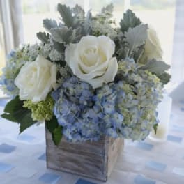 White roses and blue hydrangeas in a wooden box
