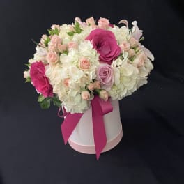 Pink and white rose bouquet in a white hat box with a magenta ribbon