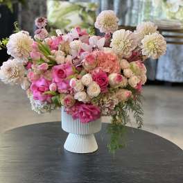 Pink and white floral arrangement in a ribbed pedestal vase