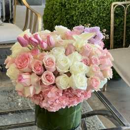 Pink and white roses with tulips and orchids in a glass vase