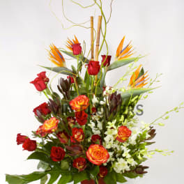 Tall floral arrangement with red roses, orange blooms, and white orchids in a red vase