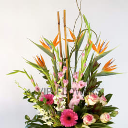 Tall tropical flower arrangement with orange bird of paradise and pink blooms in a basket