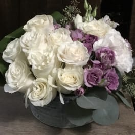 White and lavender roses arranged in a low round box
