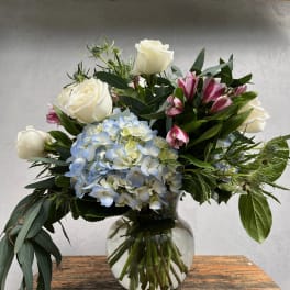 White roses and blue hydrangea in a glass vase