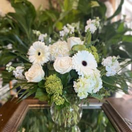 White roses and gerbera daisies arranged in a glass vase