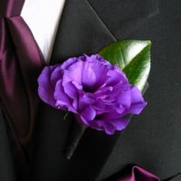 Purple boutonniere on a black suit jacket with a satin ribbon