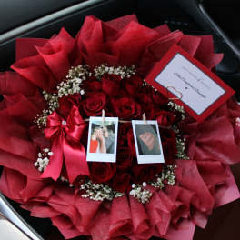 Bouquet of red roses with baby’s breath, ribbon, and photo clips in a car seat