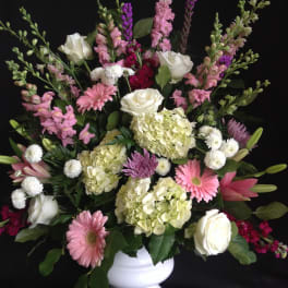 Mixed pink and white floral arrangement in a white vase