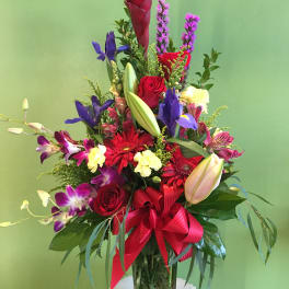 Tall mixed bouquet in a glass vase with red, purple, and yellow flowers