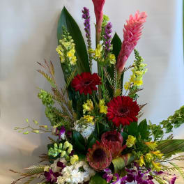 Tall tropical flower arrangement with pink ginger, red gerberas, and purple orchids
