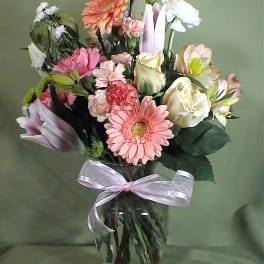 Mixed pink and white flowers in a glass vase with a ribbon