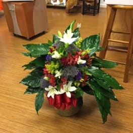 Mixed flower arrangement in a low container with white lilies and red blooms