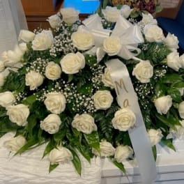 Large white rose casket spray with ribbon bows and baby's breath