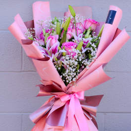 Pink bouquet of roses and lilies wrapped in pink paper