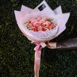 Pink rose bouquet wrapped in pale pink paper with a ribbon