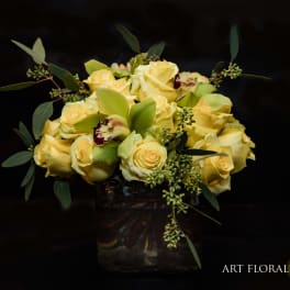Yellow rose bouquet in a glass vase with green foliage