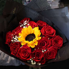 Bouquet of red roses with a yellow sunflower in black wrapping