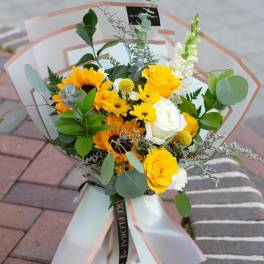 Bouquet of yellow and white flowers wrapped in translucent paper