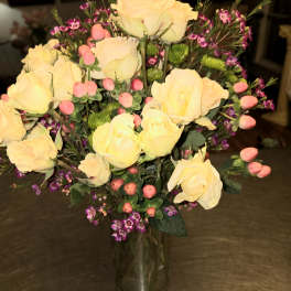 Yellow roses in a clear glass vase with pink filler flowers
