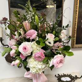 Pink and white floral arrangement in a glass vase with a pink ribbon