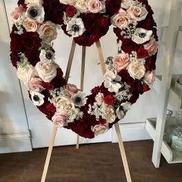 Heart-shaped floral wreath of red, blush, and white roses on an easel