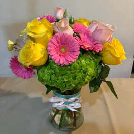 Bouquet of pink gerbera daisies and yellow roses in a glass vase