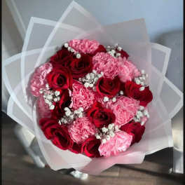 Bouquet of red roses and pink carnations wrapped in white paper
